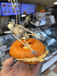 Pumpkin bagel with pumpkin cream cheese and Halloween skeleton decoration at Fast Bagel.