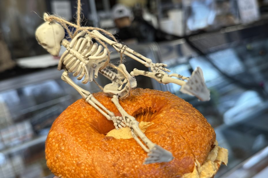Pumpkin bagel with pumpkin cream cheese and Halloween skeleton decoration at Fast Bagel.