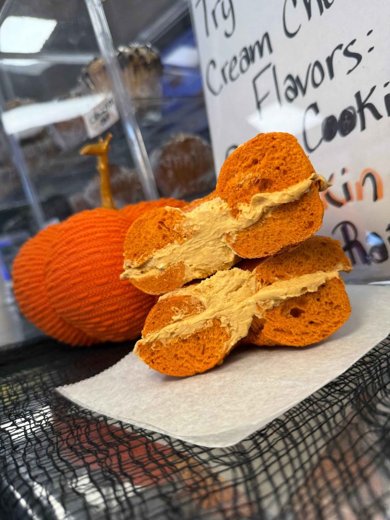 A pumpkin bagel made with whole wheat fresh bread smeared with lots of cream cheese
