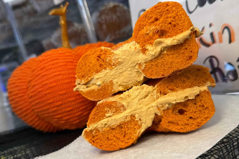 A pumpkin bagel made with whole wheat fresh bread smeared with lots of cream cheese