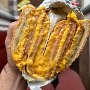 Hearty breakfast sandwich with two layers of egg, American cheese, and sliced meat on a fresh bagel, perfect for Thanksgiving mornings from Fast Bagel.