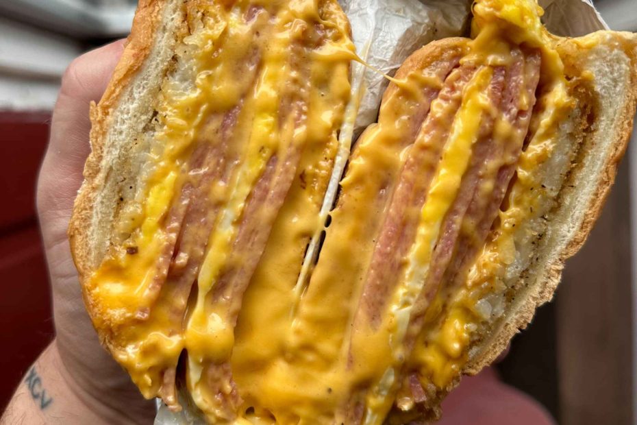 Hearty breakfast sandwich with two layers of egg, American cheese, and sliced meat on a fresh bagel, perfect for Thanksgiving mornings from Fast Bagel.