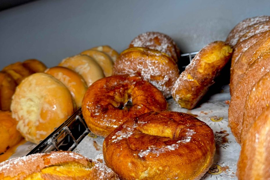 Golden brown freshly baked bagels with a light sugar glaze displayed on a bakery tray at Fast Bagel