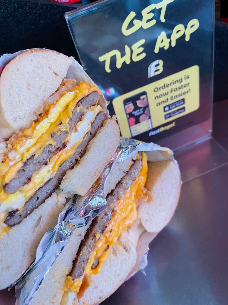 Fast Bagel app beside a breakfast sandwich and coffee.